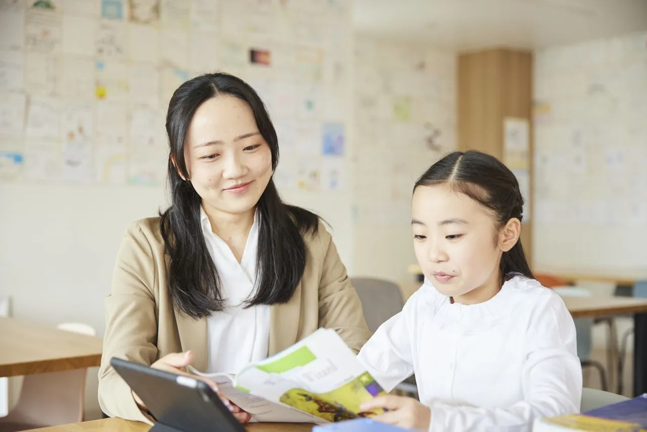 バイリンガル教師と一対一で洋書を読む小学生