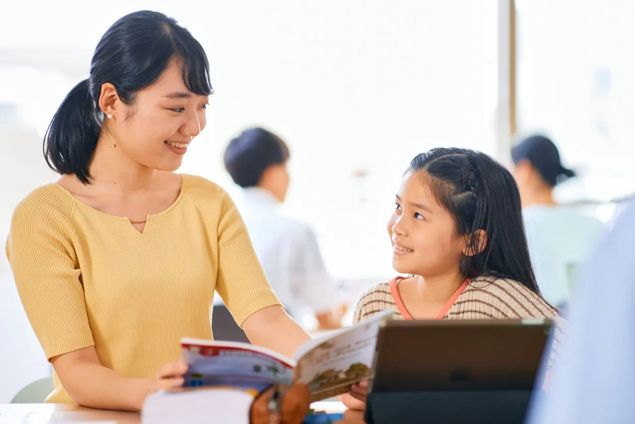 バイリンガル教師と小学生が洋書を読んでいる様子