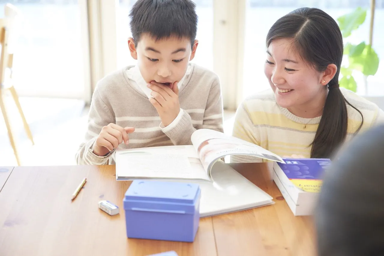 バイリンガル教師と一緒に英語の本を読み、考えている生徒